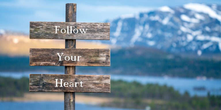 wooden signs that say Follow Your Heart with mountain and lake in the background