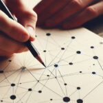 hand holding pencil and connecting dots on a sheet of paper on a table